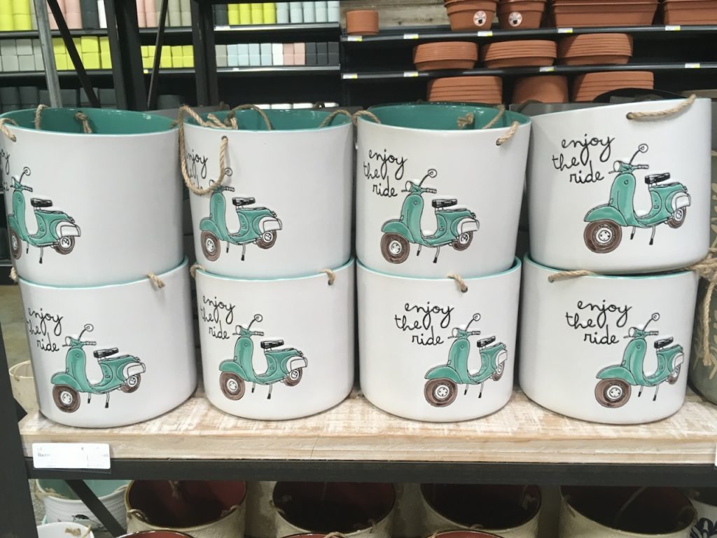 Several large ceramic planters on a shelf read "enjoy the ride" with an aqua-colored vintage scooter, photo ©Kate Dana
