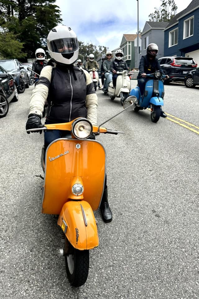 Scooterella founder Kate Dana wearing riding gear sits on a 1973 Vespa Primavera during a scooter rally, photo ©Kate Dana