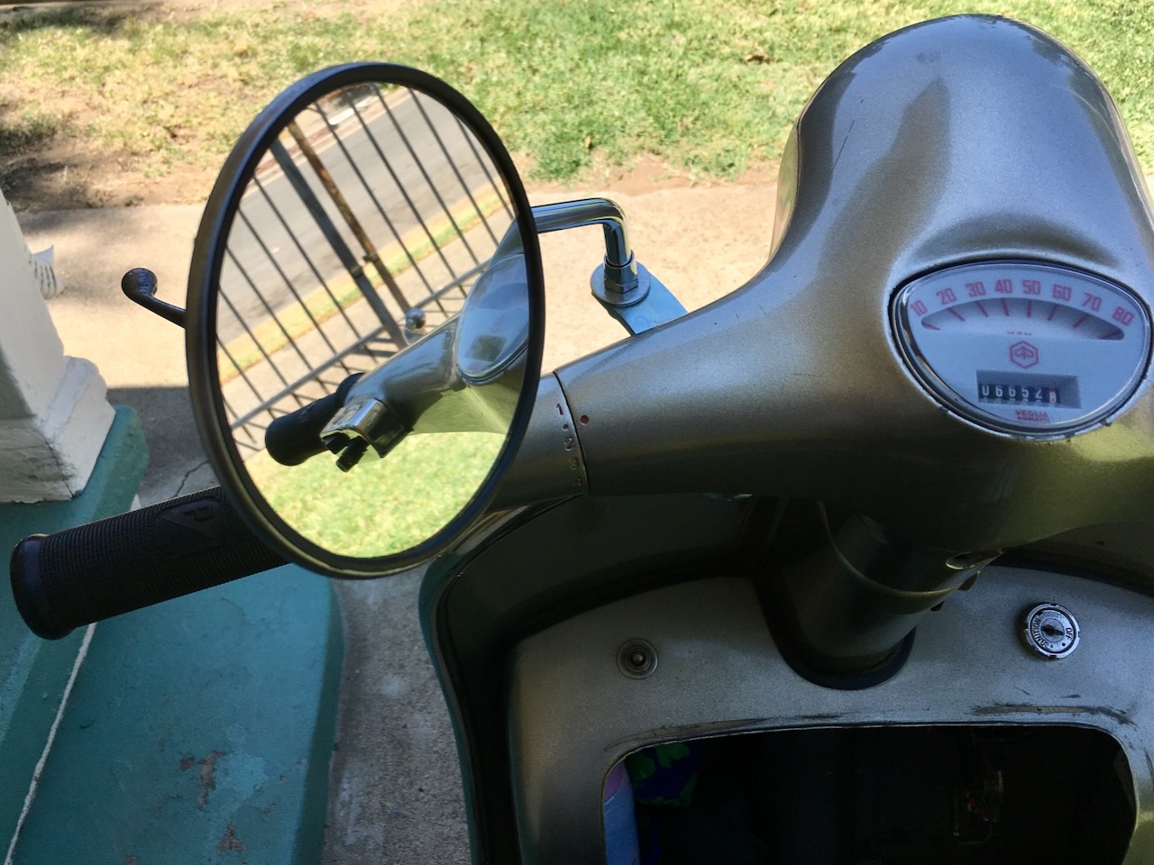 A rear view mirror reflects the handlebars of a 1966 Vespa 150, photo ©Kate Dana