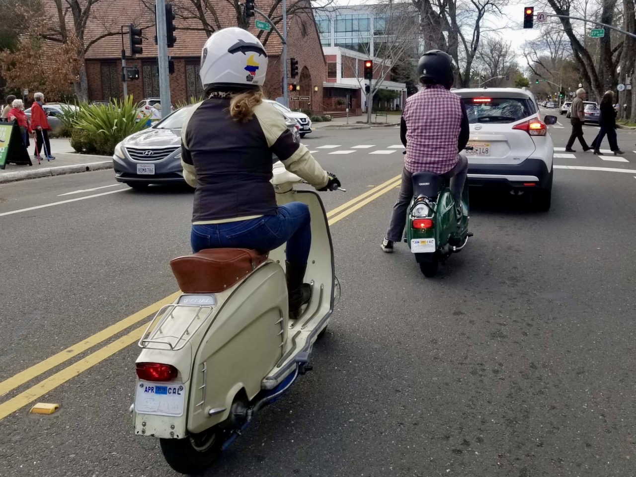 A woman riding a vintage Lambretta stops next to a person on a vintage Vespa at a traffic light, photo ©Lee Jackson