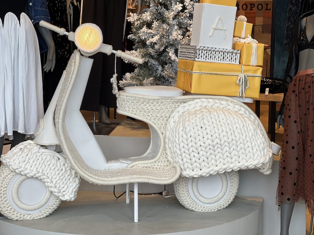A large, cream-colored cable knit replica scooter in a shop window, photo ©Kate Dana