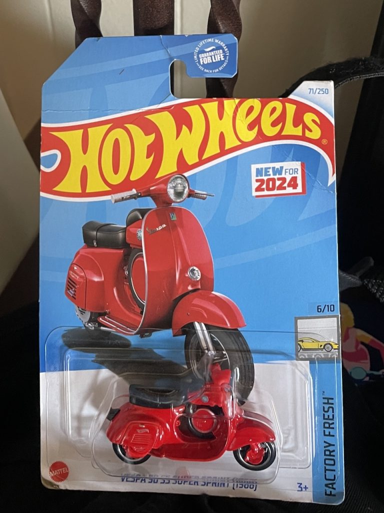A Hot Wheels card with a red model SS Vespa scooter, photo ©Kate Dana